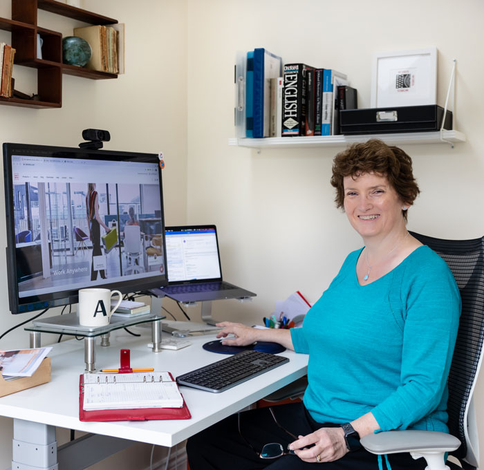 Article writer Alison Harmer in a turquoise top sat at a desk with a screen