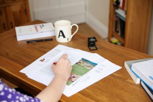 Proofs on a desk with a mug and loupe