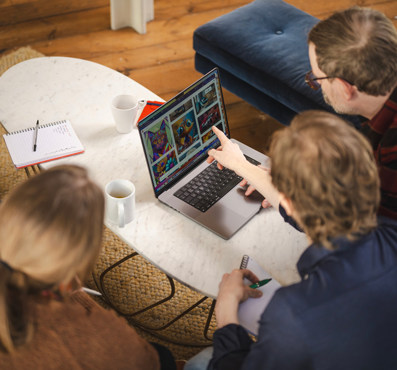 The backs of 3 heads in a creative agency looking at a laptop