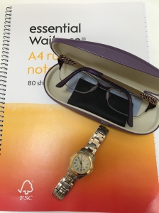 A freelance writer's notepad, watch and glasses