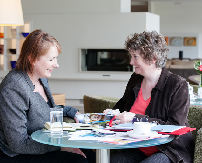 Copywriter Alison Harmer in a red shirt seated opposite a female client across a table