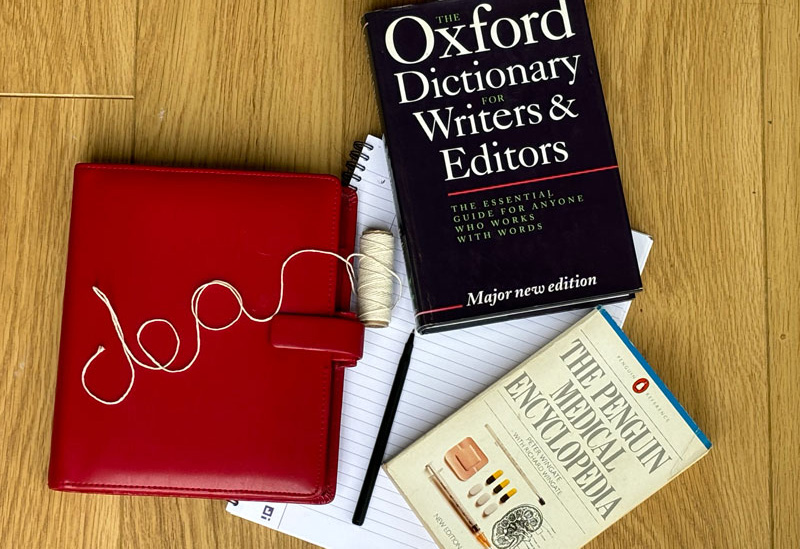 Healthcare copywriter books on a table, including a medical dictionary and a dictionary for writers and printers