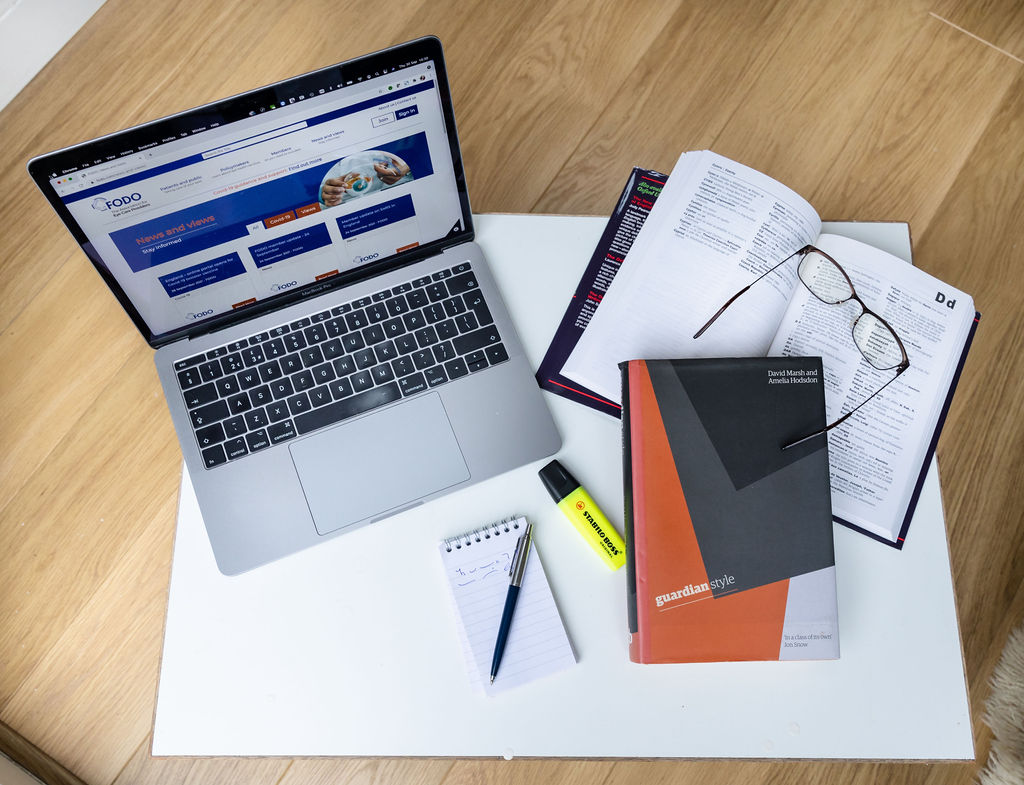 Newsletter writer's desk with laptop, notebook, glasses and a book