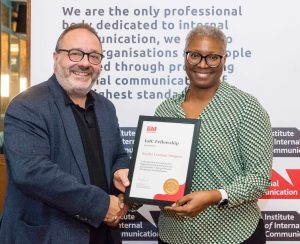 Sandra Lowman-Simpson, wearing a green and cream blouse, is pictured right receiving her Fellowship from Dominic Walters of the IoIC in a dark grey suit jacket.