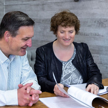 Copywriter Alison Harmer flicking through a magazine with a male at a table