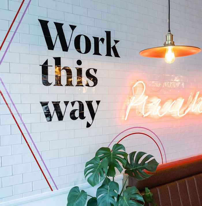 Wall sign saying 'Work this way' in black type to illustrate how freelance copywriter Alison Harmer works