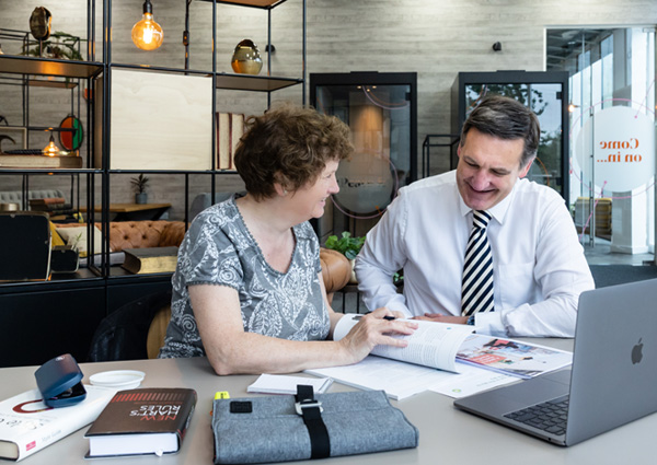 Alison Harmer at a desk sat next to a male client demonstrating her copywriting services.