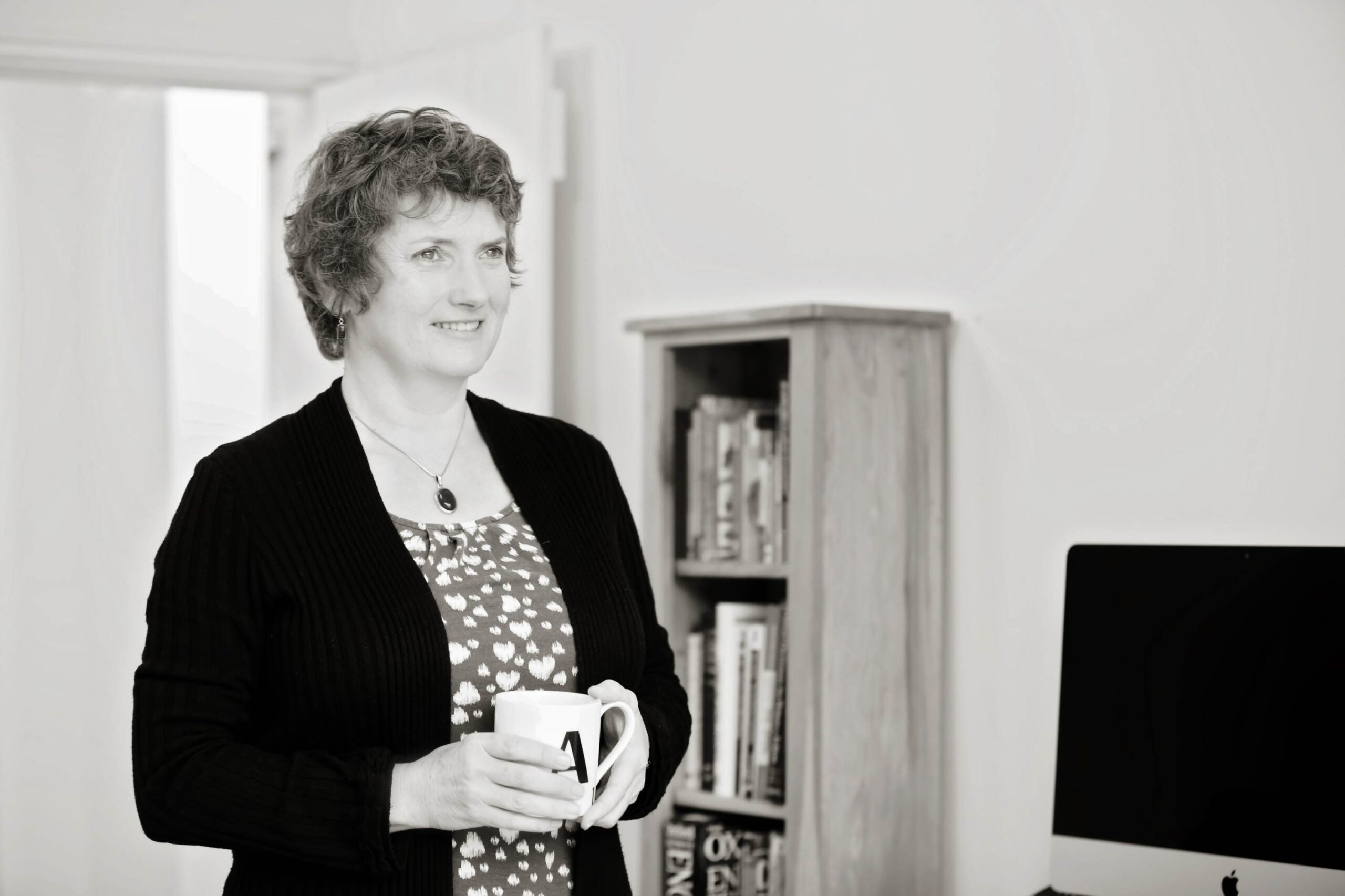 Alison Harmer standing next to a bookcase working from home