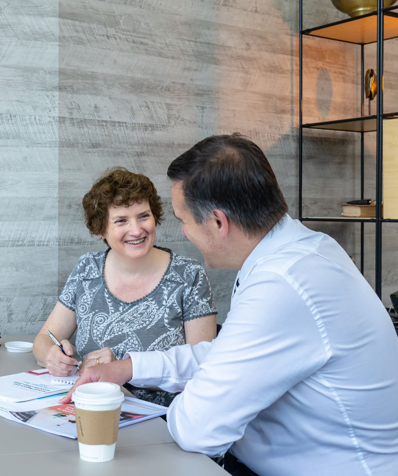 Alison Harmer chats to a male client in an office.