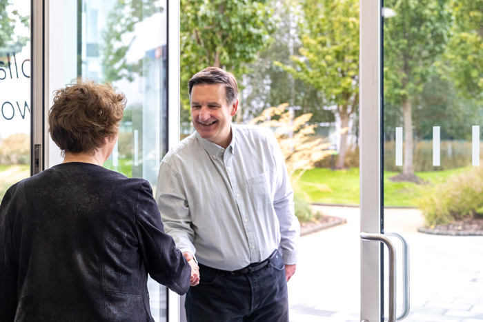 A man shaking hands with sector-specific copywriter Alison Harmer standing at an open office door